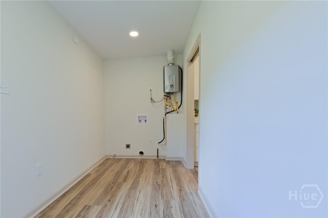 washroom with hookup for a washing machine, hookup for an electric dryer, light wood-style flooring, tankless water heater, and baseboards