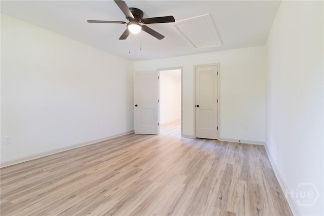 spare room with a ceiling fan, attic access, light wood-style floors, and baseboards
