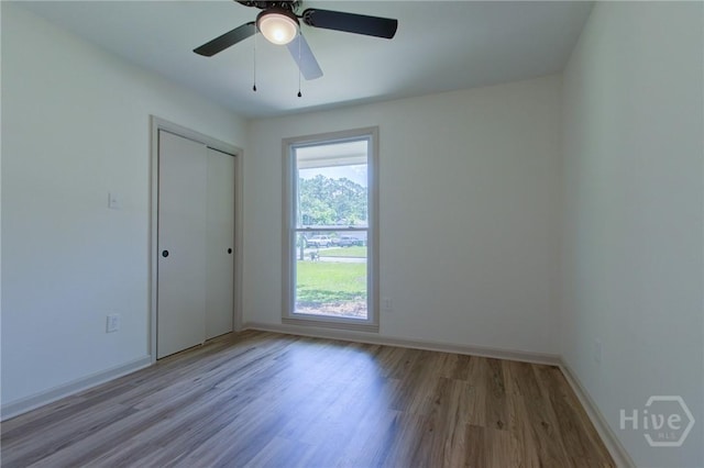 empty room with wood finished floors, baseboards, and a ceiling fan
