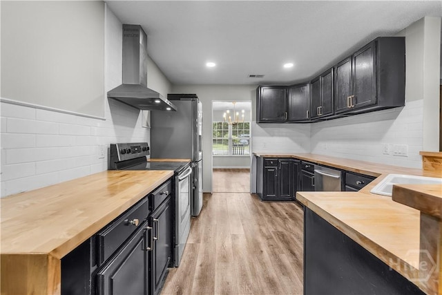 407 Middleton St, Pooler, GA 31322 - kitchen with butcher block countertops, stainless steel appliances, wall chimney exhaust hood, light wood-type flooring, and dark cabinetry