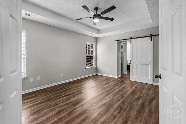 407 Middleton St, Pooler, GA 31322 - unfurnished bedroom with a barn door, dark wood-style floors, a textured ceiling, a raised ceiling, and baseboards