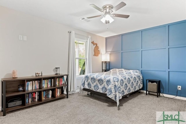 carpeted bedroom featuring ceiling fan and a decorative wall