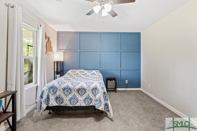 carpeted bedroom featuring a decorative wall, baseboards, and ceiling fan