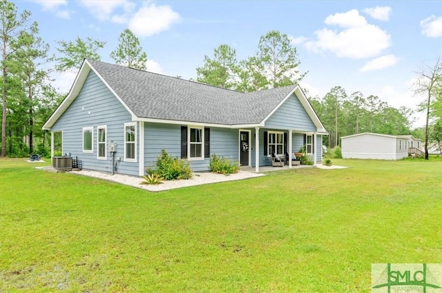 back of property with a yard, roof with shingles, and central AC