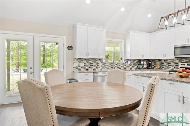 kitchen featuring stainless steel appliances, white cabinets, tasteful backsplash, french doors, and pendant lighting
