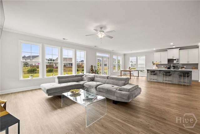 living room featuring crown molding, wood finished floors, recessed lighting, baseboards, and ceiling fan