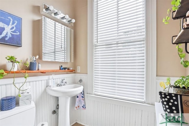 546548 E Huntingdon St, Savannah, GA 31401 - bathroom featuring wainscoting, toilet, a decorative wall, and a sink