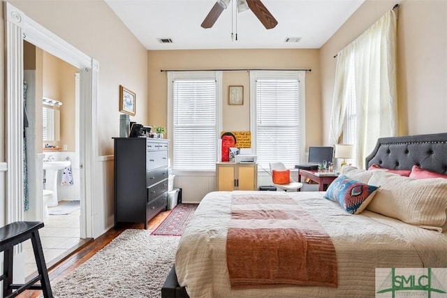 546548 E Huntingdon St, Savannah, GA 31401 - bedroom with wood finished floors, multiple windows, wainscoting, connected bathroom, and a sink