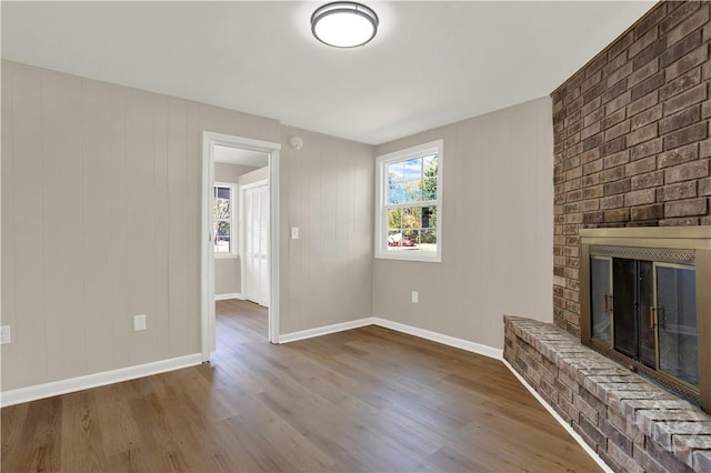 unfurnished living room with wood finished floors, a fireplace, and baseboards