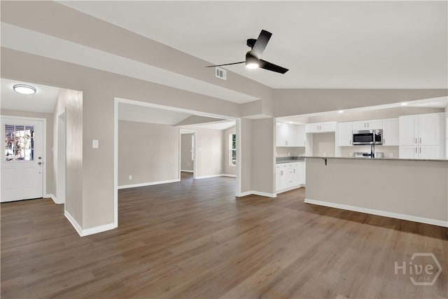 unfurnished living room featuring lofted ceiling, a ceiling fan, wood finished floors, and baseboards