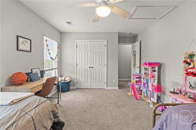 carpeted bedroom featuring a closet, baseboards, ceiling fan, and attic access