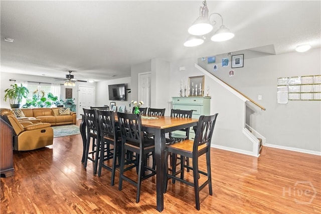 dining room featuring a ceiling fan, wood finished floors, stairway, and baseboards