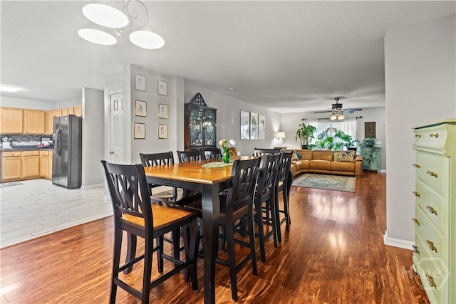 dining room featuring wood-type flooring, ceiling fan, and baseboards