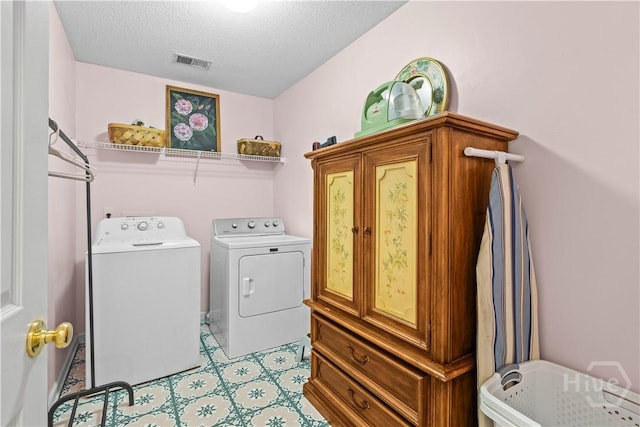 clothes washing area featuring washing machine and dryer, a textured ceiling, and cabinet space