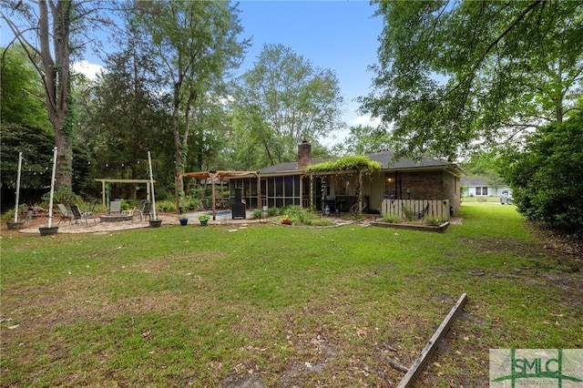 view of grassy yard featuring a sunroom and a patio area