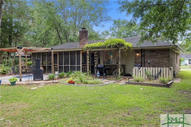 back of property featuring a patio area, a chimney, a sunroom, and a lawn