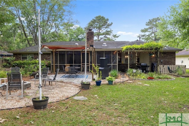 back of house with a patio, a sunroom, a lawn, and a chimney