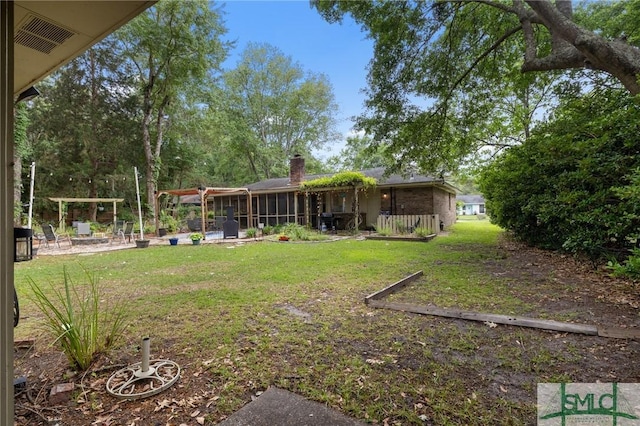 view of green lawn with a patio area and an outdoor fire pit