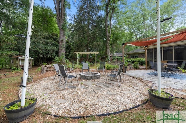 view of patio / terrace featuring a fire pit, an outdoor structure, and a sunroom