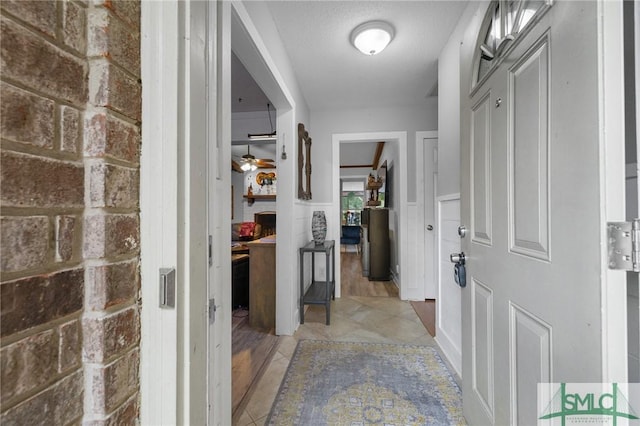 corridor featuring a wainscoted wall and light tile patterned flooring