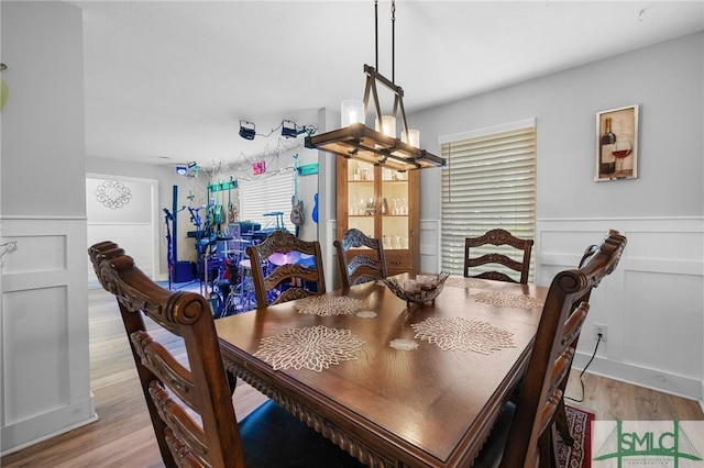 dining area featuring wood finished floors, wainscoting, and a decorative wall