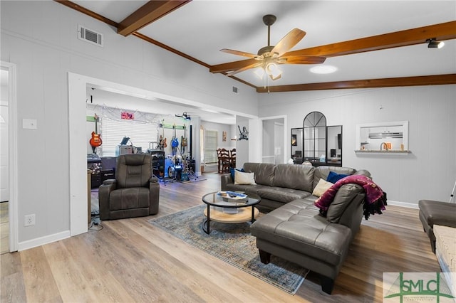 living area featuring beam ceiling, a ceiling fan, wood finished floors, baseboards, and a decorative wall
