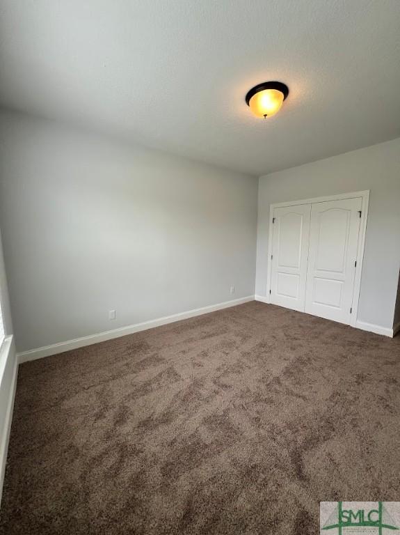 unfurnished bedroom featuring carpet flooring, baseboards, and a closet