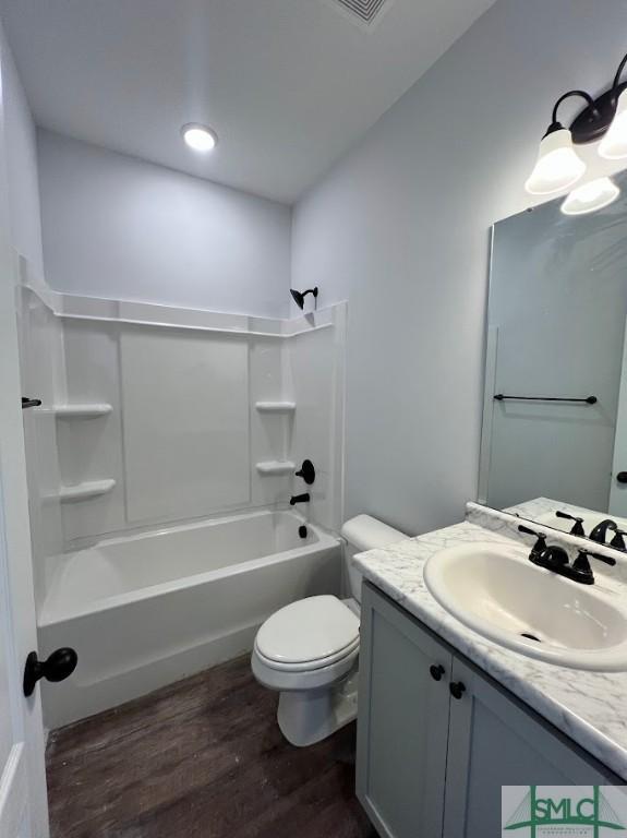 bathroom featuring wood finished floors, toilet, vanity, and washtub / shower combination
