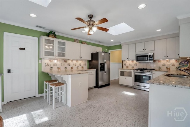 506 Butler Ave, Tybee Island, GA 31328 - kitchen with appliances with stainless steel finishes, a skylight, a sink, a peninsula, and decorative backsplash