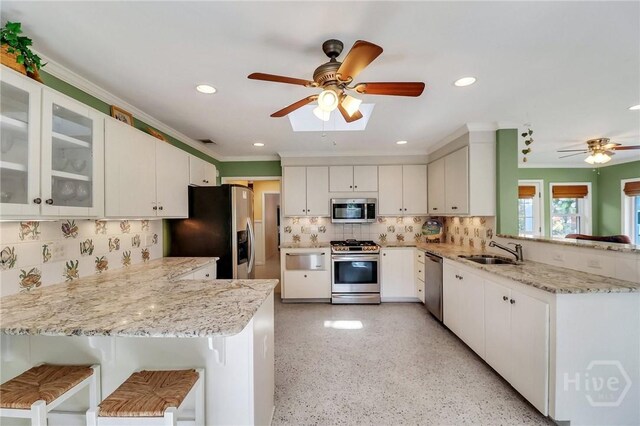 506 Butler Ave, Tybee Island, GA 31328 - kitchen featuring stainless steel appliances, a peninsula, a sink, a ceiling fan, and tasteful backsplash