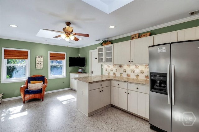 506 Butler Ave, Tybee Island, GA 31328 - kitchen with stainless steel fridge, a peninsula, a ceiling fan, a skylight, and white cabinets