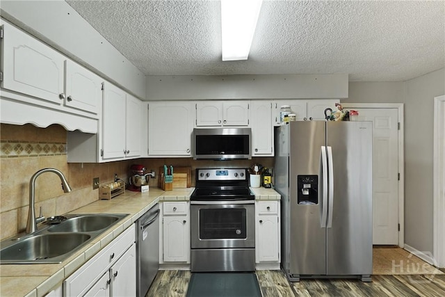1405 Desert Storm Dr, Hinesville, GA 31313 - kitchen with appliances with stainless steel finishes, a sink, tile countertops, a textured ceiling, and wood finished floors
