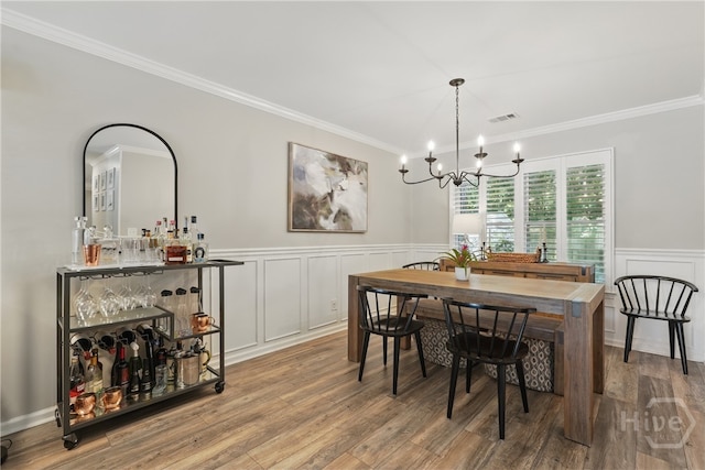 129 Penn Sta, Savannah, GA 31410 - dining area with crown molding, a chandelier, wainscoting, wood finished floors, and a decorative wall