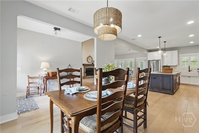 dining area with recessed lighting, light wood-style flooring, a chandelier, a fireplace, and baseboards