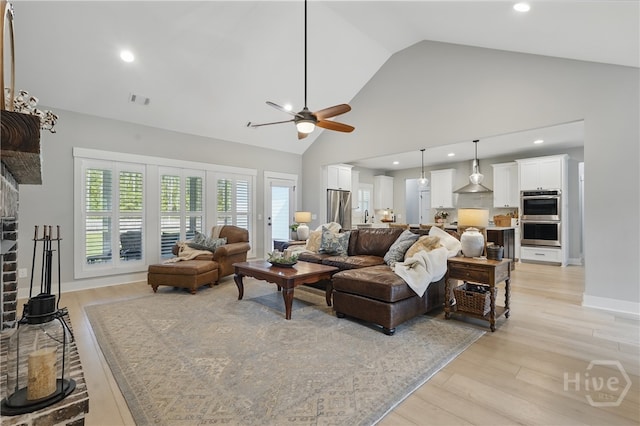 living area featuring a ceiling fan, a fireplace, light wood-style floors, high vaulted ceiling, and recessed lighting