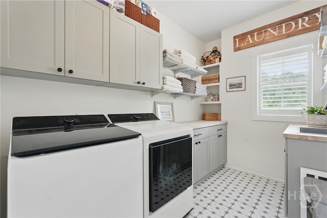 laundry room with cabinet space, washer and clothes dryer, light flooring, and baseboards