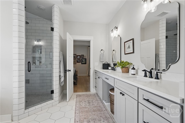 bathroom with a shower stall, double vanity, tile patterned flooring, and baseboards