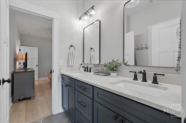 full bathroom with double vanity, baseboards, and wood finished floors