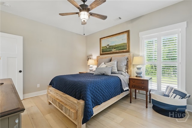 bedroom with light wood finished floors, baseboards, and a ceiling fan