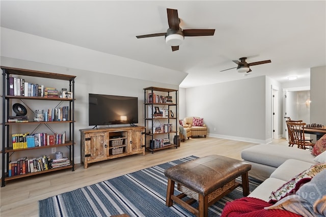 living area with a ceiling fan, wood finished floors, and baseboards