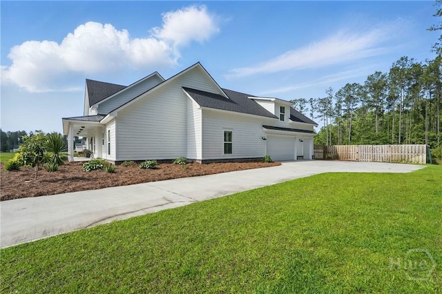 view of side of home featuring driveway, an attached garage, and roof with shingles