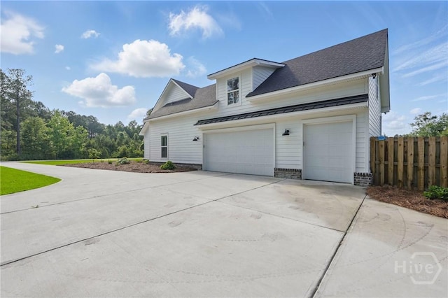 view of side of property with a standing seam roof, driveway, fence, metal roof, and a shingled roof