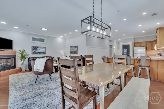 5 17th St, Tybee Island, GA 31328 - dining room featuring light tile patterned floors, crown molding, recessed lighting, and a fireplace with raised hearth