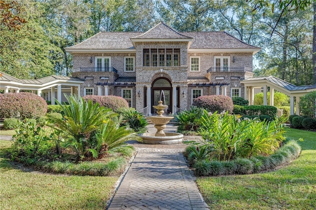 view of front of property with brick siding, a high end roof, and french doors