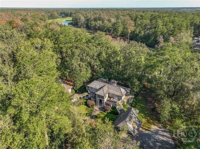 aerial view of property and surrounding area featuring a heavily wooded area and a large body of water