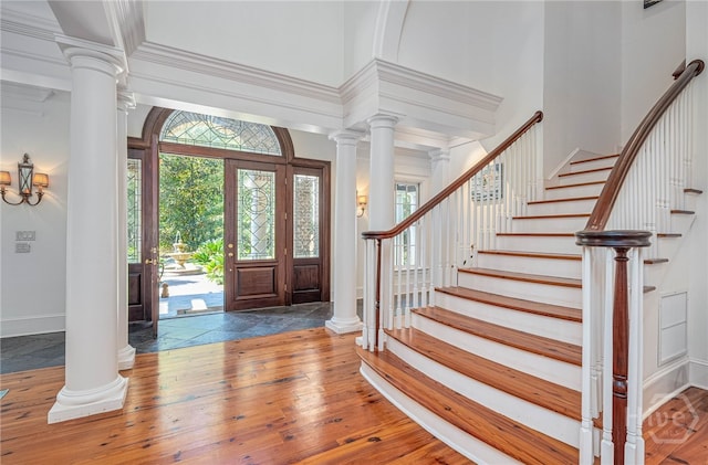 entrance foyer featuring stairs, baseboards, hardwood / wood-style flooring, a high ceiling, and decorative columns