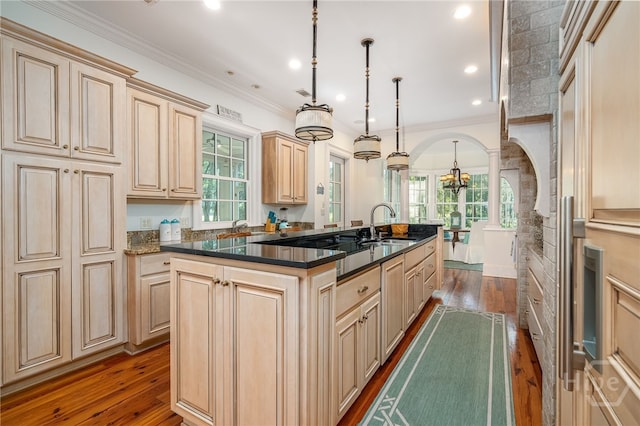 kitchen featuring dark wood finished floors, a kitchen island with sink, healthy amount of natural light, cream cabinets, and crown molding