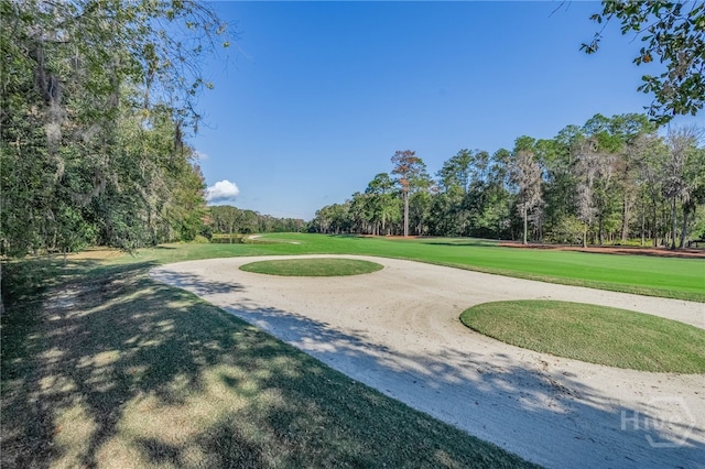 surrounding community featuring view of scattered trees, golf course view, and a yard