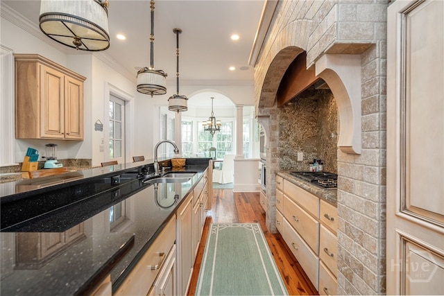 kitchen with a sink, stainless steel gas stovetop, light brown cabinets, ornamental molding, and light wood finished floors