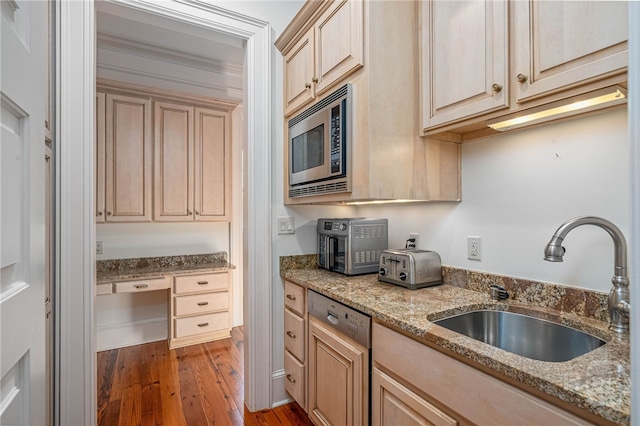 kitchen featuring stainless steel microwave, dishwashing machine, a sink, wood finished floors, and light stone counters